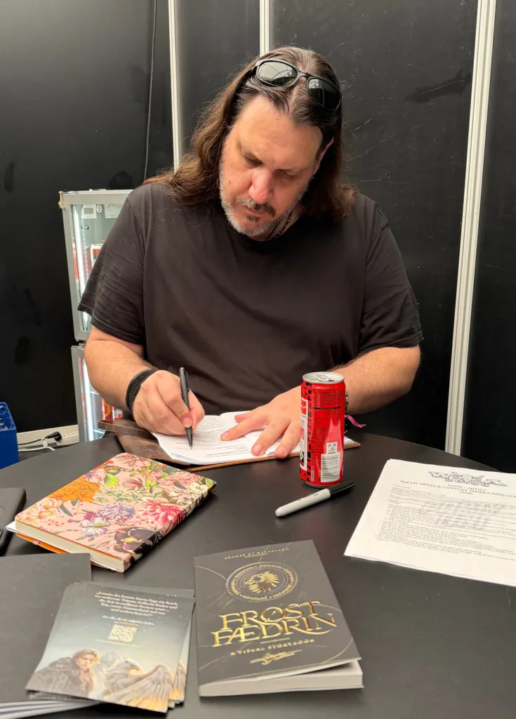 Maxim Matthew signiert Bücher am Tisch