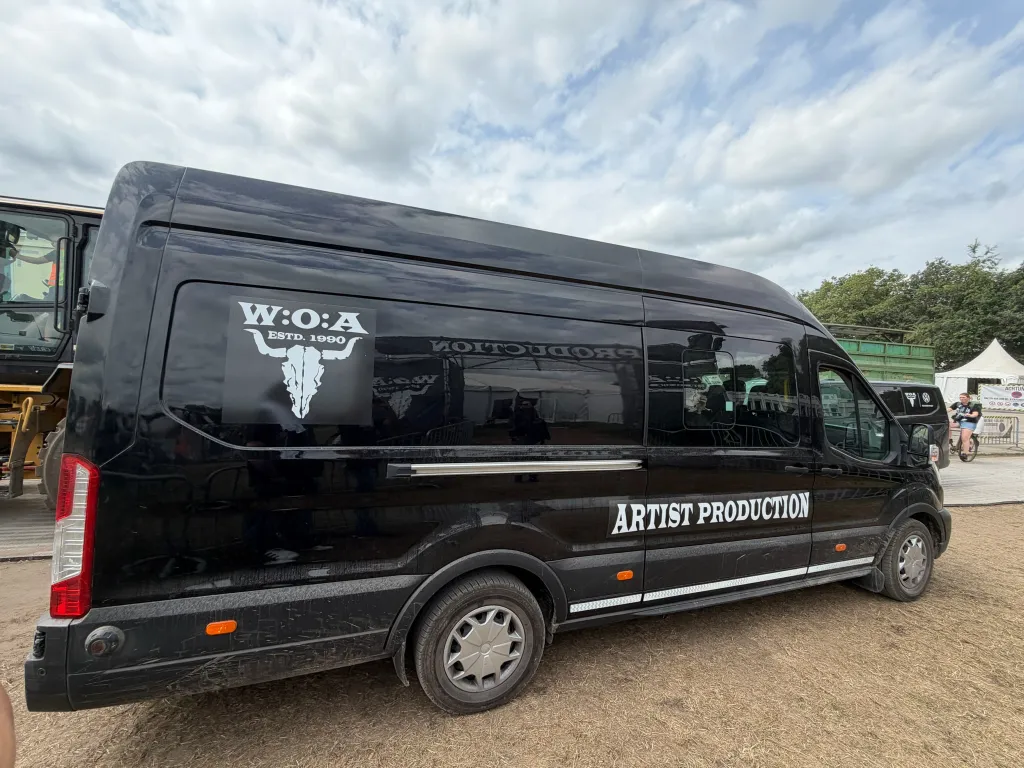 Ein schwarzer Transporter mit W:O:A-Logo und der Aufschrift „Artist Production“.